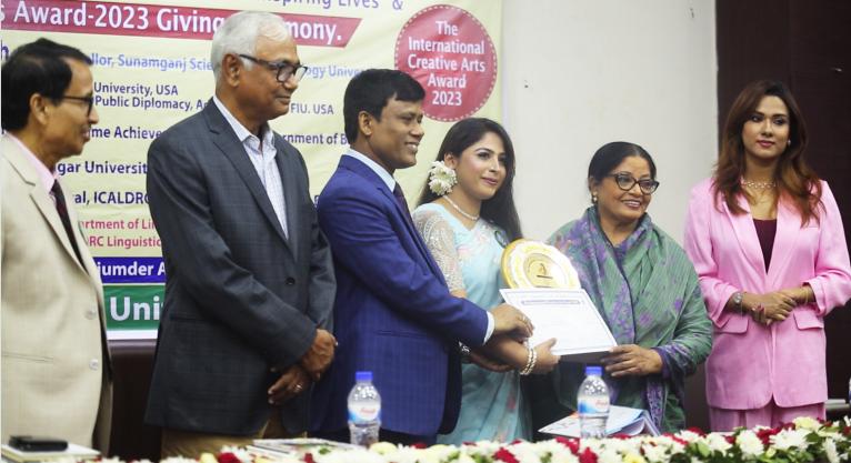 শামছুন নাহার আহমেদ এর পক্ষে ICALDRC এর বাঙ্গলাদেশি কর্মকর্তা তানজিনা ফেরদৌস পদক ও সার্টিফিকেট গ্রহণ করেন।